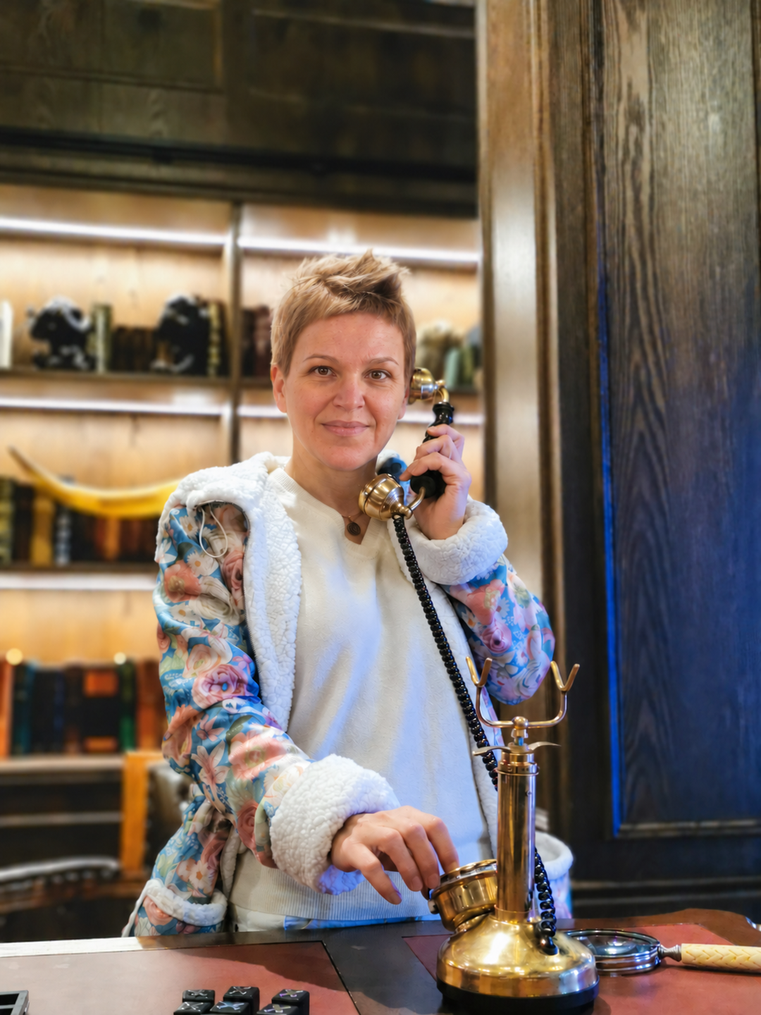 My floral parka open over a white knit top, showing the white faux-fur hood and sleeve ends while I hold a telephone receiver.