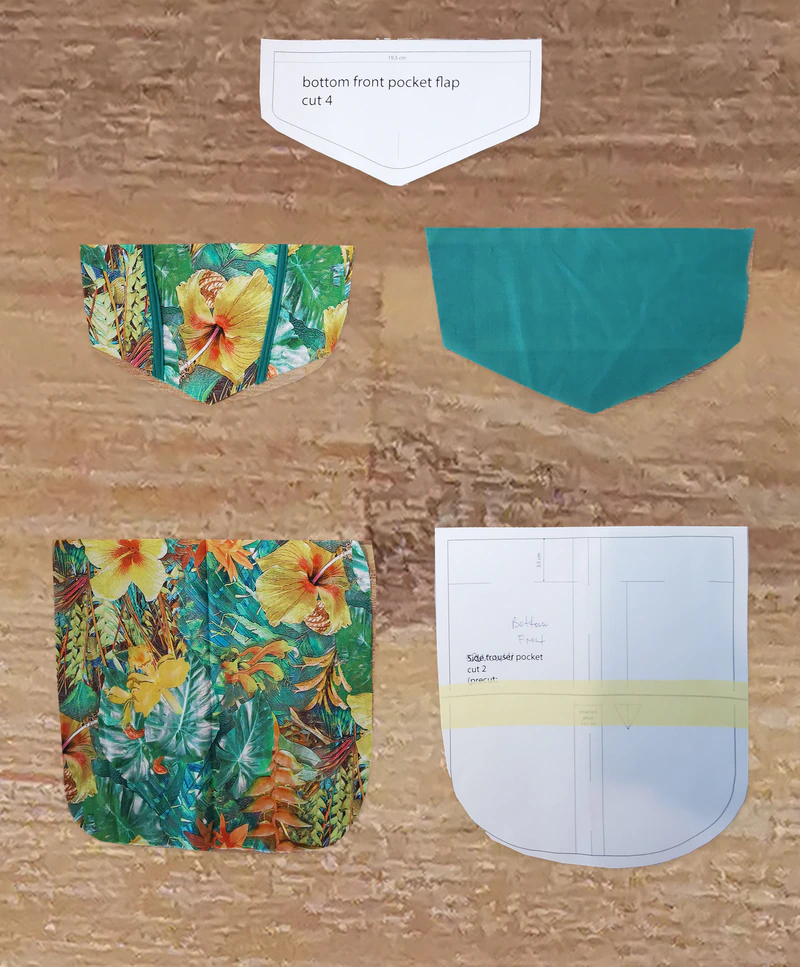 The pocket, pieced flap and green flap lining beside the paper pieces.