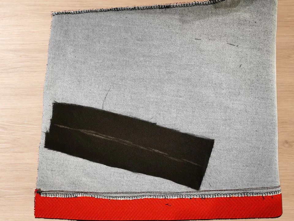 Black interfacing strip over the marked opening area on the grey wrong side of the trouser front.