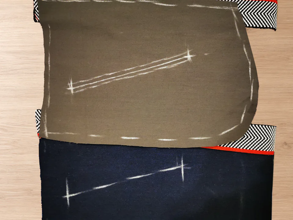 Brown pocket lining shifted aside on a navy trouser front, revealing the opening markings on both pieces.