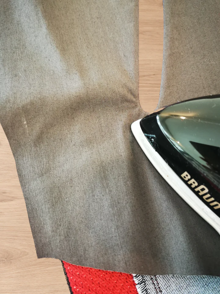 The point of an iron pressing a rounded end of the turned opening on the brown lining side.