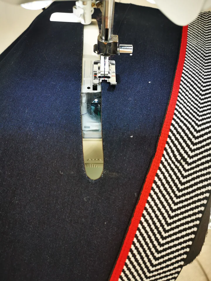 Machine edgestitching the navy edge around an empty faced pocket opening.