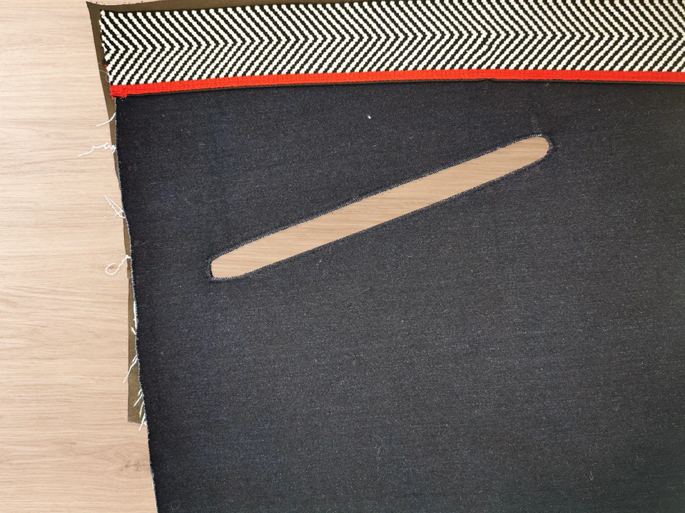 Navy trouser front showing a rounded empty window with a completed line of edgestitching close to its edge.