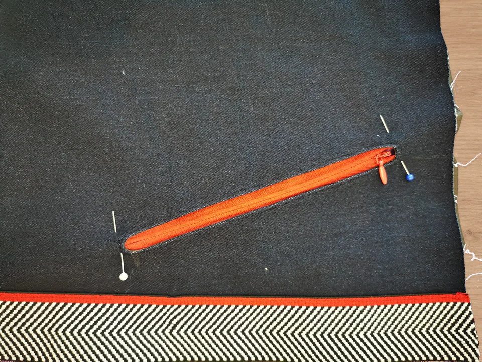 Red zipper pinned behind the opening as seen from the navy outside of the trousers.