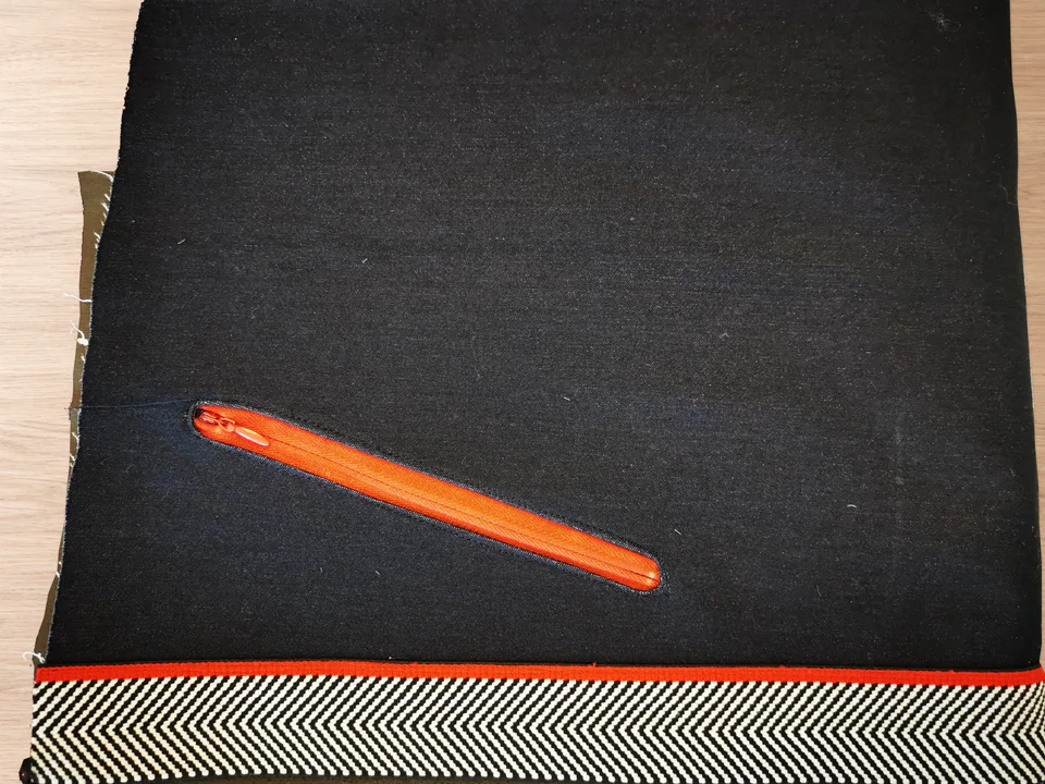 Red zipper fitted into a rounded opening in the navy trouser front beside the striped side detail.