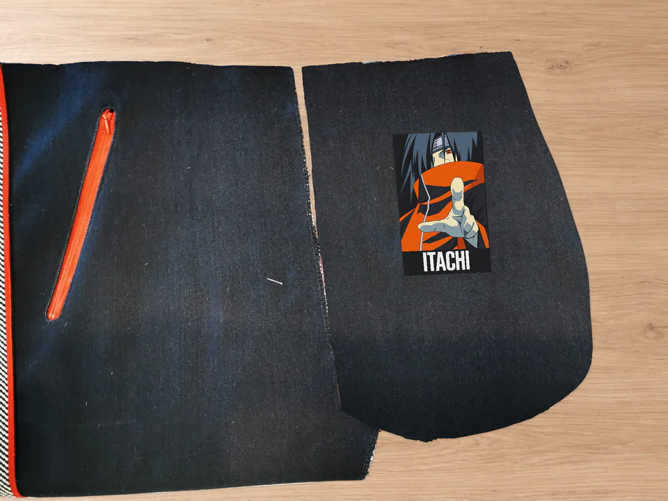 Placement illustration with the orange-collared Itachi design and extended hand, matching the motif visible in the finished pocket.
