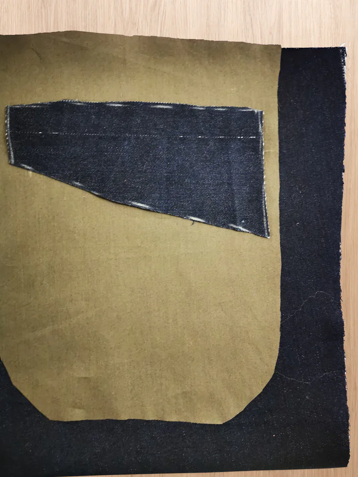 A navy main-fabric pocket facing laid over the right side of a brown pocket-bag backing, before sewing.