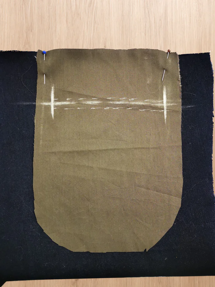 Plain brown lining pinned right sides together to the navy trouser back, with the pocket opening marked on the lining.
