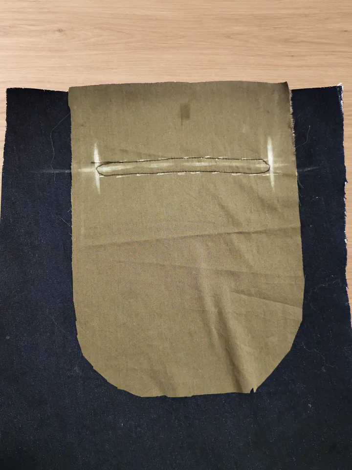 Stitched rounded back-pocket opening in brown lining, with the centre fabric still intact.