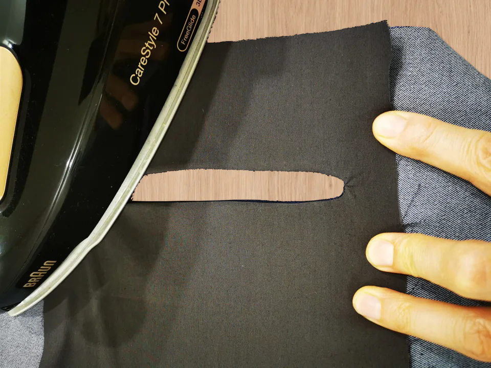 Iron pressing brown lining around a turned back-pocket opening.