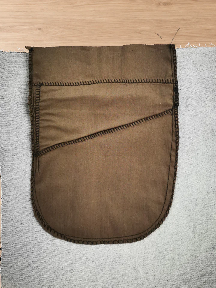 Inside of the completed back pocket: brown bag with a curved sewn outline and overlocking along its outer edge.